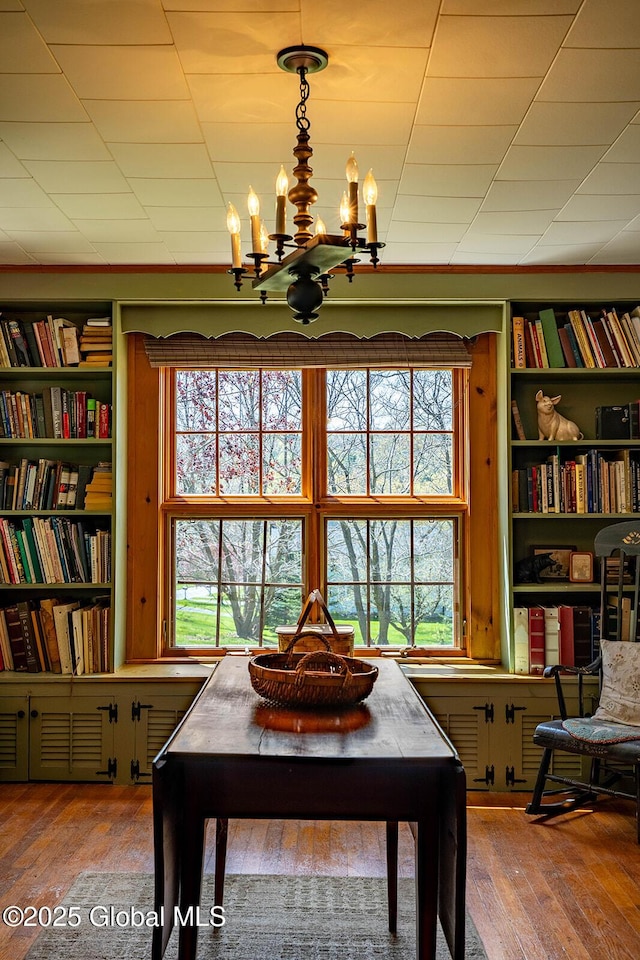 interior space featuring an inviting chandelier, built in shelves, and hardwood / wood-style flooring