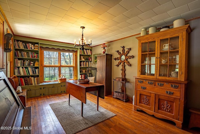 home office featuring crown molding, a notable chandelier, and hardwood / wood-style flooring
