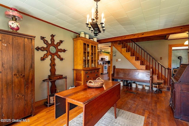 dining space featuring visible vents, crown molding, wood finished floors, an inviting chandelier, and stairs