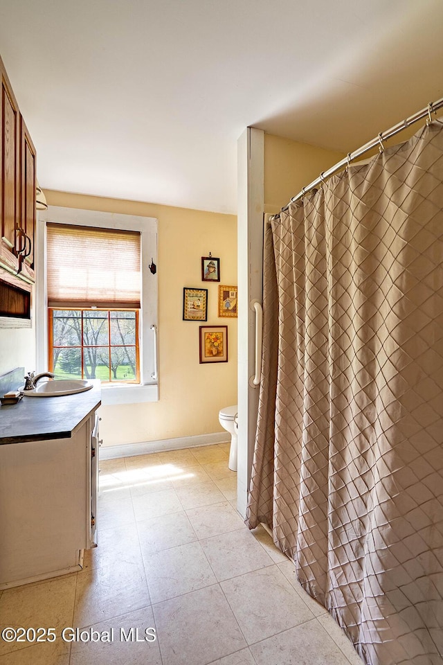 full bathroom with baseboards, vanity, and toilet