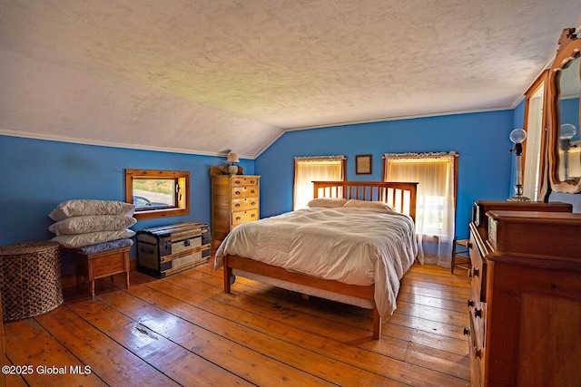 bedroom with a textured ceiling, vaulted ceiling, and hardwood / wood-style floors