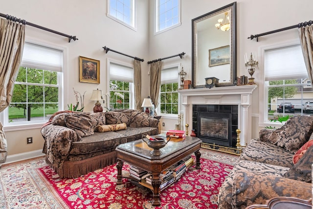 living room featuring a tile fireplace, baseboards, wood finished floors, and a towering ceiling