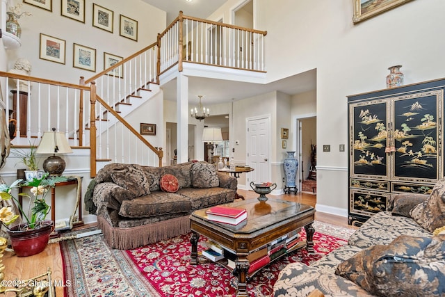living room with a high ceiling, stairs, wood finished floors, and a chandelier