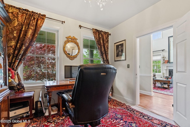 office featuring baseboards, wood finished floors, and a fireplace