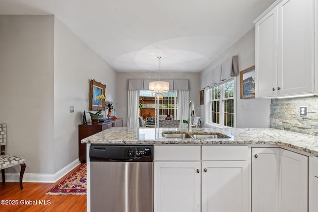 kitchen with stainless steel dishwasher, a sink, light wood-style flooring, a peninsula, and white cabinets