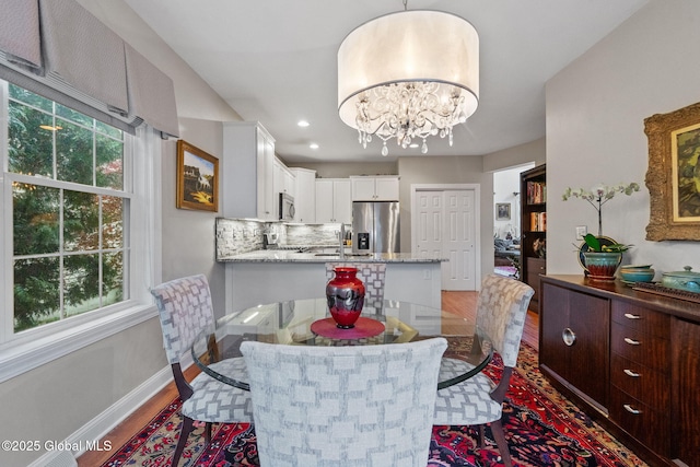 dining space with wood finished floors, a chandelier, baseboards, and recessed lighting