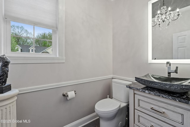 half bath with toilet, vanity, and a chandelier