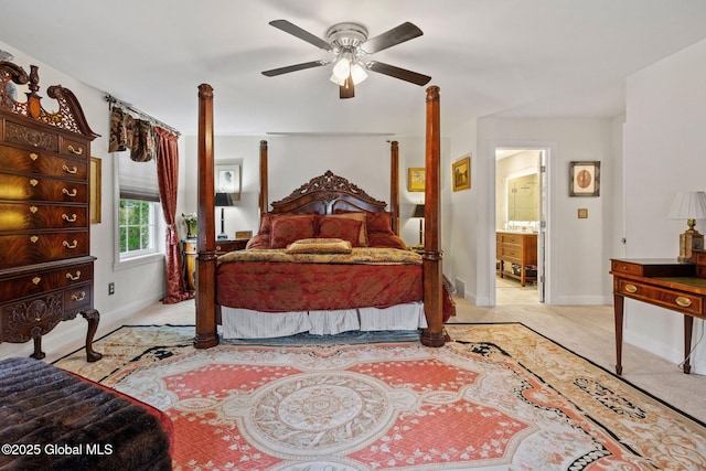 bedroom with light colored carpet, baseboards, ceiling fan, and ensuite bath