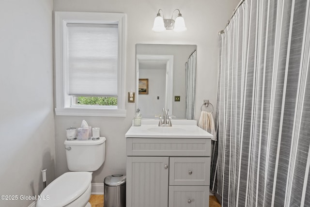 bathroom with vanity, toilet, curtained shower, and baseboards
