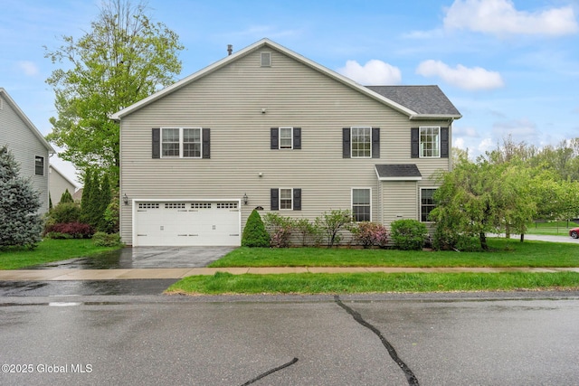 view of front of house with an attached garage, asphalt driveway, and a front lawn