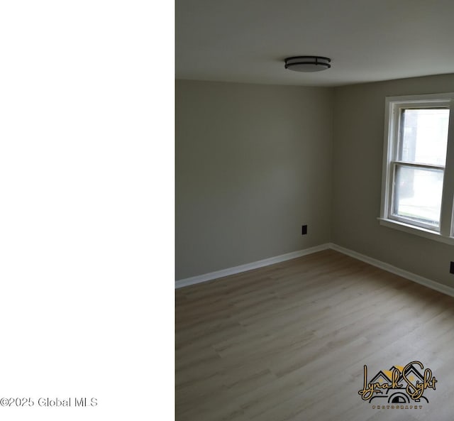 spare room with baseboards and wood finished floors