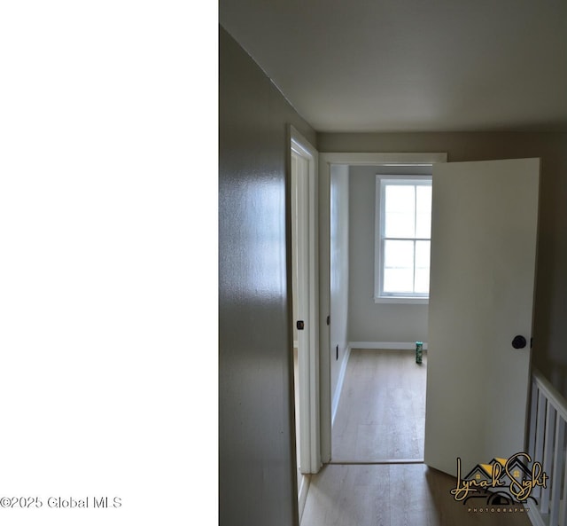 corridor featuring baseboards and wood finished floors