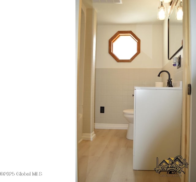 bathroom featuring visible vents, tile walls, wood finished floors, vanity, and toilet