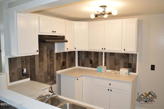 kitchen with decorative backsplash, under cabinet range hood, and white cabinets
