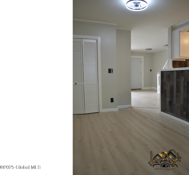 interior space with baseboards, ornamental molding, and light wood-style flooring