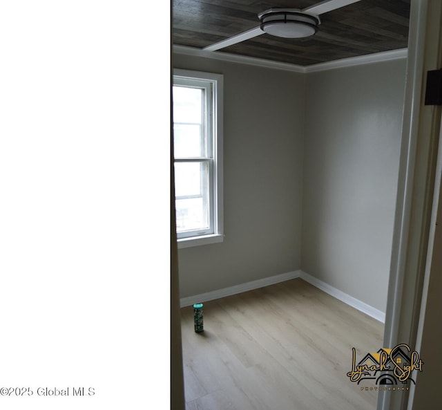 spare room featuring baseboards, crown molding, and wood finished floors