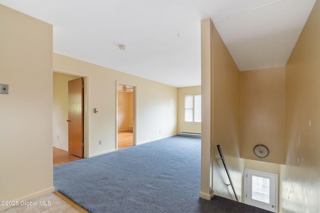 carpeted empty room featuring baseboard heating, baseboards, and a smoke detector