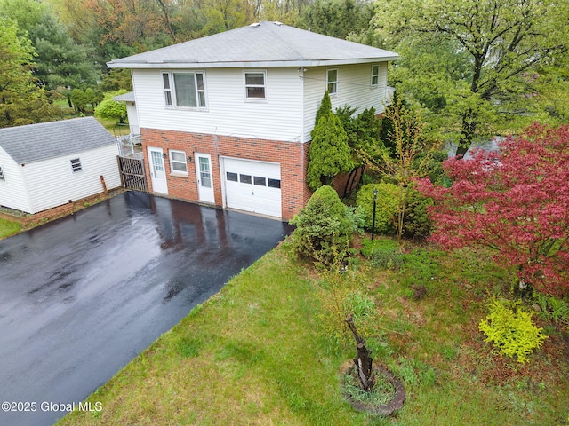 view of property exterior with driveway, brick siding, a garage, and a wooded view