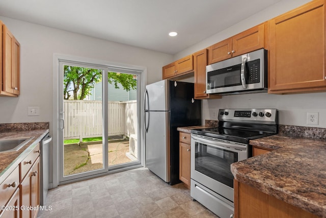 kitchen with dark countertops, appliances with stainless steel finishes, brown cabinetry, and recessed lighting
