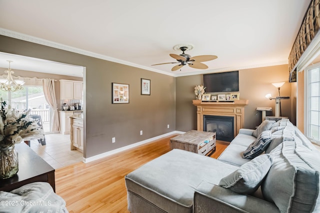 living area with ornamental molding, ceiling fan with notable chandelier, and light wood-style floors