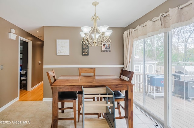 dining space with an inviting chandelier, baseboards, and light tile patterned floors