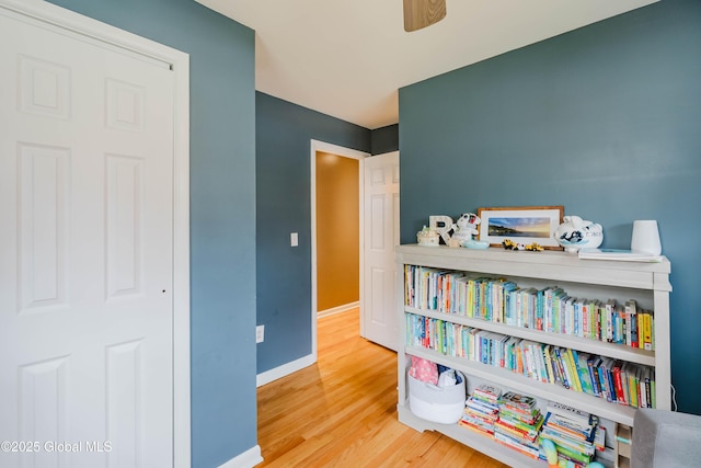 recreation room featuring baseboards, a ceiling fan, and wood finished floors