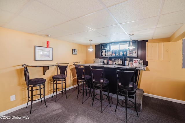 bar featuring baseboards, wet bar, and a drop ceiling