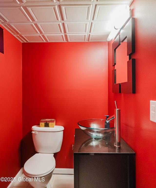 half bathroom featuring toilet, baseboards, and vanity