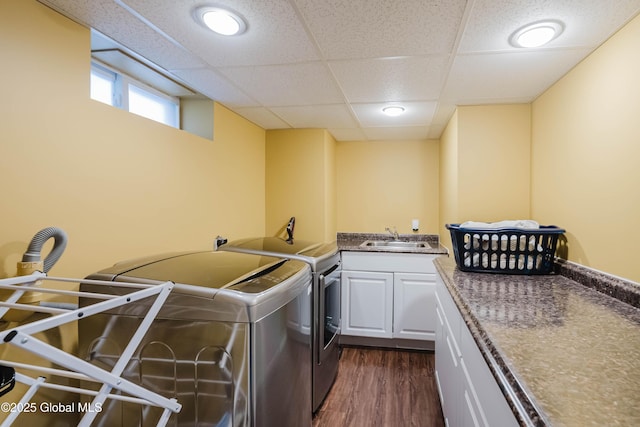 laundry area featuring dark wood-style floors, washing machine and dryer, cabinet space, and a sink