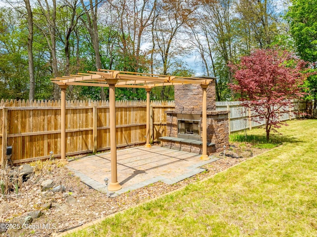 view of yard with an outdoor stone fireplace, a pergola, fence, and a patio
