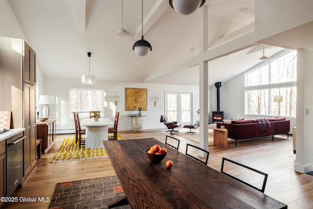 829 Jefferson Rd, Nassau, NY 12123 - dining room with beamed ceiling, a wood stove, light wood-style flooring, and high vaulted ceiling