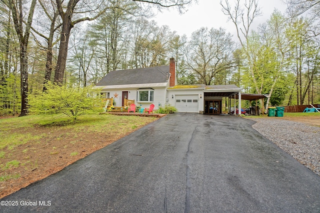 view of front of house with driveway, a garage, a chimney, and an attached carport