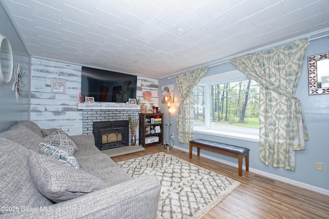 living area featuring baseboards, wood finished floors, and a fireplace
