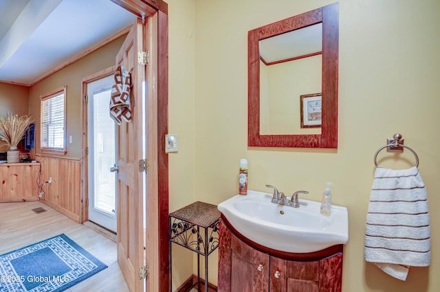 bathroom with wood finished floors, vanity, and wainscoting