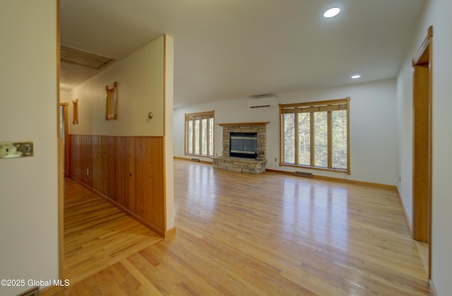 unfurnished living room with a wall mounted AC, wainscoting, wood finished floors, and visible vents
