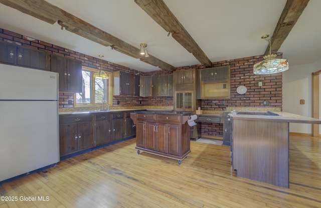 kitchen featuring a center island, freestanding refrigerator, light wood finished floors, and brick wall