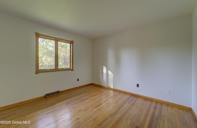 spare room with baseboards, light wood-style flooring, and visible vents