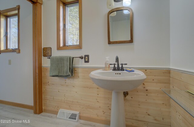 bathroom featuring wooden walls, a wealth of natural light, and visible vents
