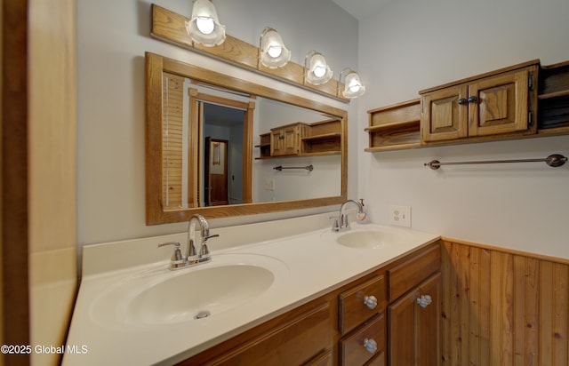 full bathroom featuring a sink, a wainscoted wall, and double vanity