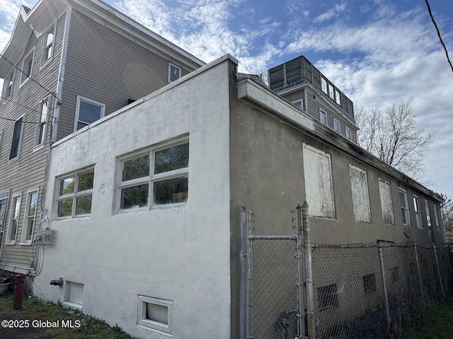 6 Spring St, Johnstown, NY 12095 - view of side of property featuring stucco siding, a gate, and fence