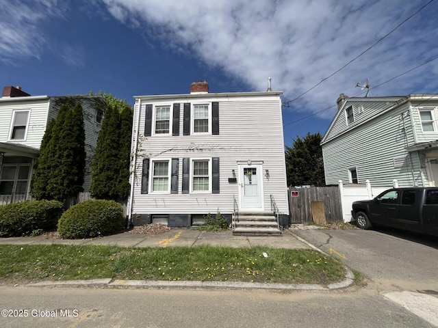 view of front of home with entry steps, fence, and a chimney