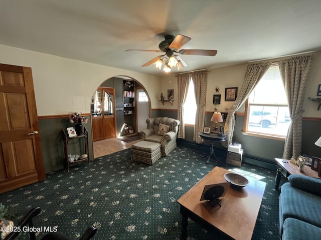 living room featuring arched walkways, ceiling fan, and carpet