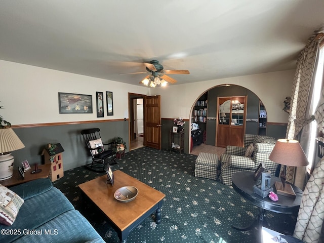 carpeted living room featuring a ceiling fan and arched walkways