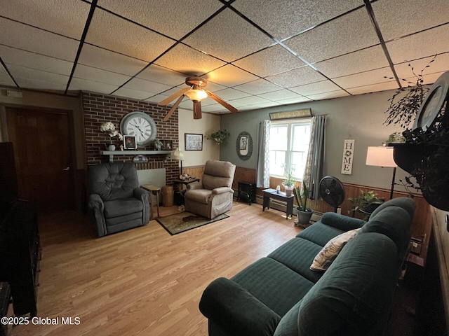 living area with wood finished floors, wainscoting, ceiling fan, and a drop ceiling