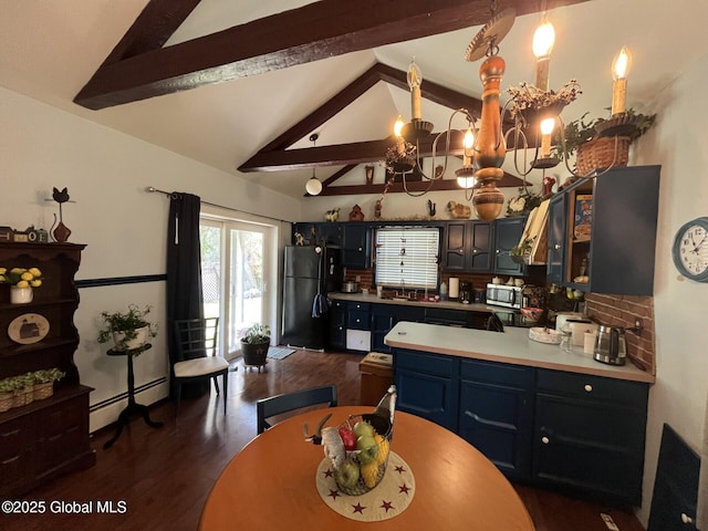 kitchen with blue cabinets, a sink, stainless steel microwave, freestanding refrigerator, and a baseboard heating unit