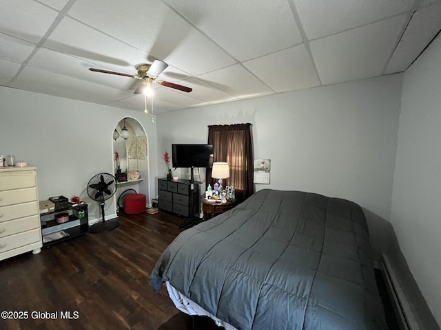 bedroom featuring baseboards, ceiling fan, wood finished floors, and a paneled ceiling