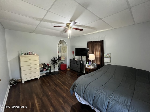 bedroom with baseboards, ceiling fan, a drop ceiling, and wood finished floors