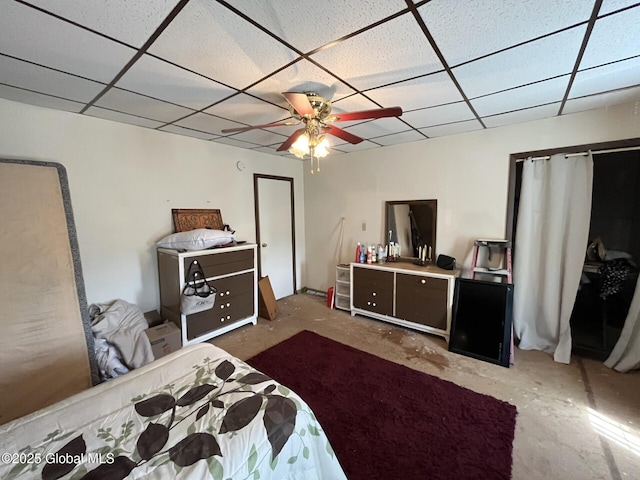bedroom with ceiling fan, unfinished concrete flooring, and a paneled ceiling