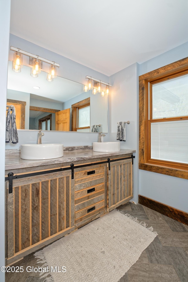 full bath featuring double vanity, a sink, and baseboards