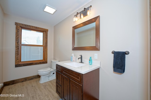 bathroom featuring vanity, baseboards, wood finished floors, and toilet